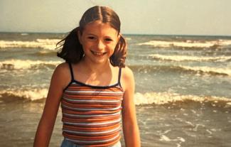 A girl on beach with waves behind her