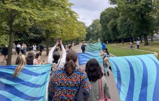 A group of people marching through a park holding flags