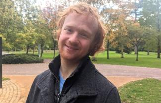 A man in a park looking at the camera and smiling