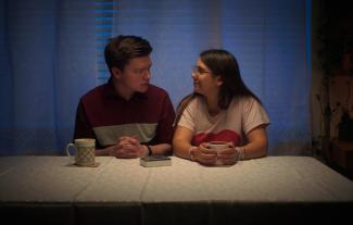 A man and a woman sitting at a table looking at each other