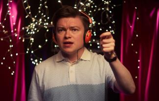 A man on a stage wearing headphones and talking