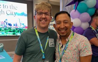 Two men wearing lanyards standing together and smiling