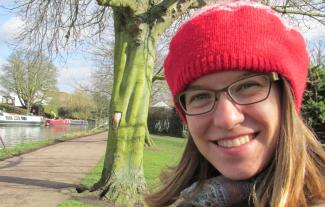 A woman sitting on a bench beside a river, smiling