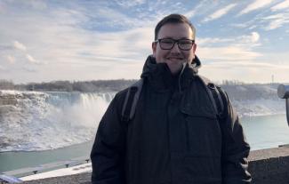 A man standing in front of a waterfall and smiling