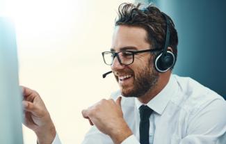 A man in a call centre wearing a phone headset and smiling