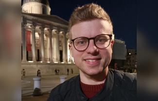 A man smiling for the camera with London's National Gallery behind him