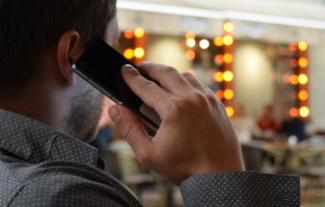 The back of a man's head as he speaks into a mobile phone. 