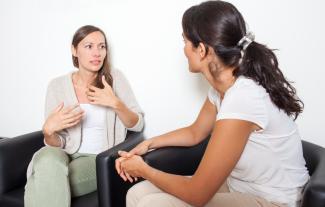 Two women sitting and talking, with one gesticulating with her hands