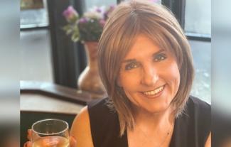 A woman smiling and holding up a glass of wine