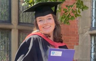 A young woman in a graduating gown, smiling