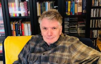 A man sitting in front of a bookshelf and smiling