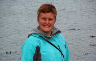 A woman smiling, with a lake behind her