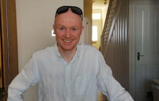 A man smiling, with sunglasses on the top of his head