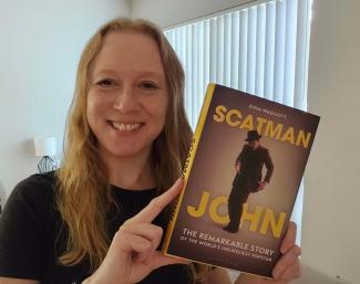 A woman holding a book and smiling