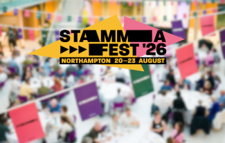 A logo saying 'STAMMAFest 2026' against a blurred picture of people seated at tables in a conference setting