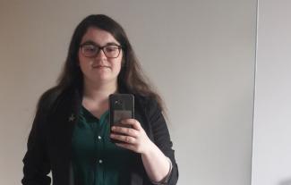 A young woman holding a mobile phone and taking a mirror picture of herself