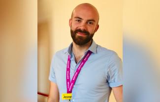 A man wearing a lanyard and smiling