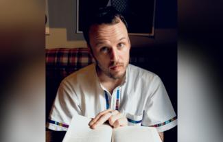 A man flicking through a book and looking at the camera