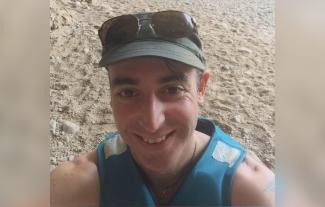 A man standing in sand, smiling