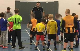 A man coaching a group of boys to play football