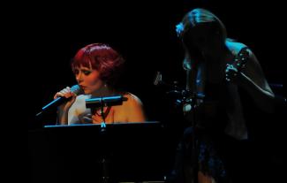 A woman at a piano singing into a microphone