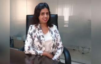 A woman siting in an office looking at the camera and smiling