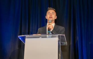 A man at a lecturn speaking into a microphone