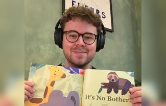 A man wearing headphones and holding up a children's book