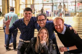 Three men and a woman huddled together and smiling