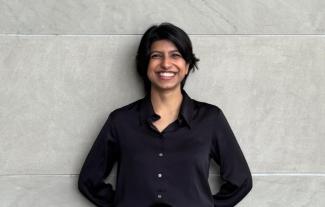 A woman leaning against a wall and smiling