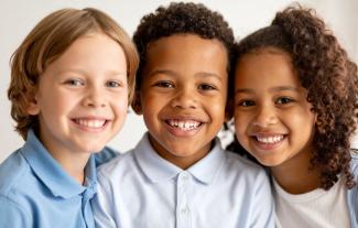 Three school aged children, two boys and a girl, smiling
