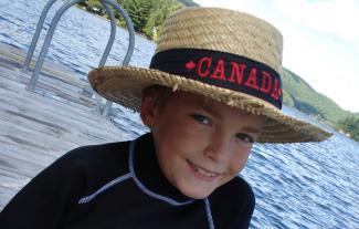 A young boy in a straw hat beside a river