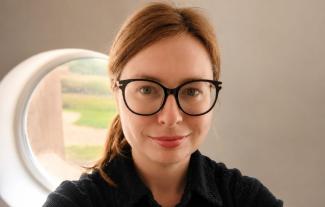 A woman wearing glasses, smiling