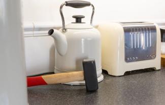 A kitchen worktop, with a toaster, a kettle and a hammer on it