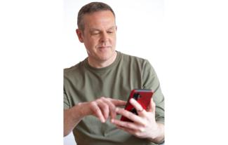 A man looking at his smartphone and pressing its screen with his finger
