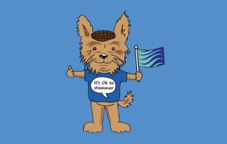 An illustrated dog wearing a t-shirt and flat cap, holding a flag. On its t-shirt it says 'It's okay to stammer'