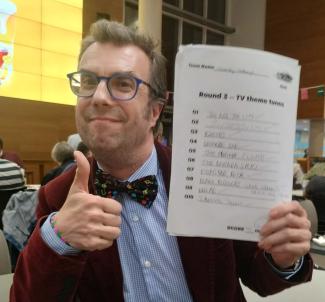 A man holding a piece of paper in one hand and doing a thumbs up with the other