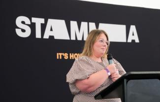 A woman standing on a stage and speaking into a microphone