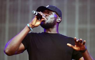 A man in a baseball cap holding a microphone to his mouth.