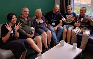 Six people sitting on a sofa and smiling