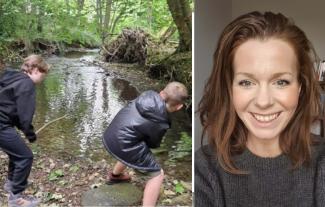 Two boys next to a woodland stream. A smiling woman's face is net to them