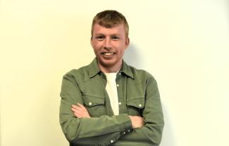 A man with his arms folded, and smiling