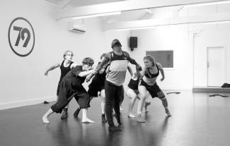 A group of dancers in a dance studio, in a huddle