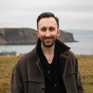 A man standing in an outdoor setting, smiling