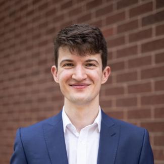 A man in front of a brick wall, smiling