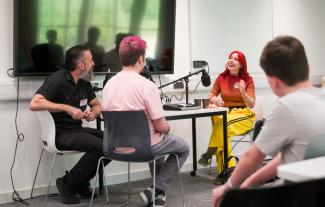 A man, a woman and a teenager sitting at a table speaking into microphones