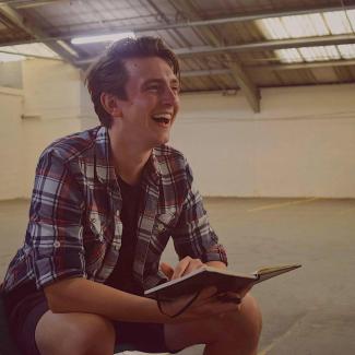 A man with a book open, laughing