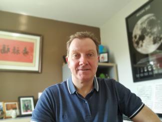 A man sitting in his office at home, smiling