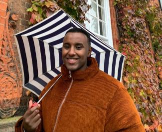 A man holding an open umbrella and smiling