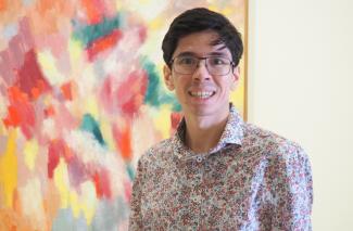 A man smiling in front of a piece of abstract art